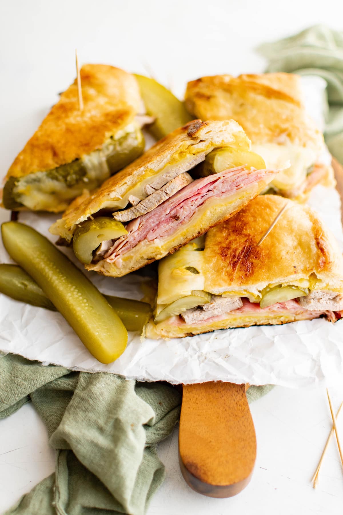 Cuban sandwiches stacked on a wood board.