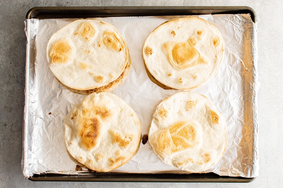 Crispy tortilla on a foil covered baking sheet.