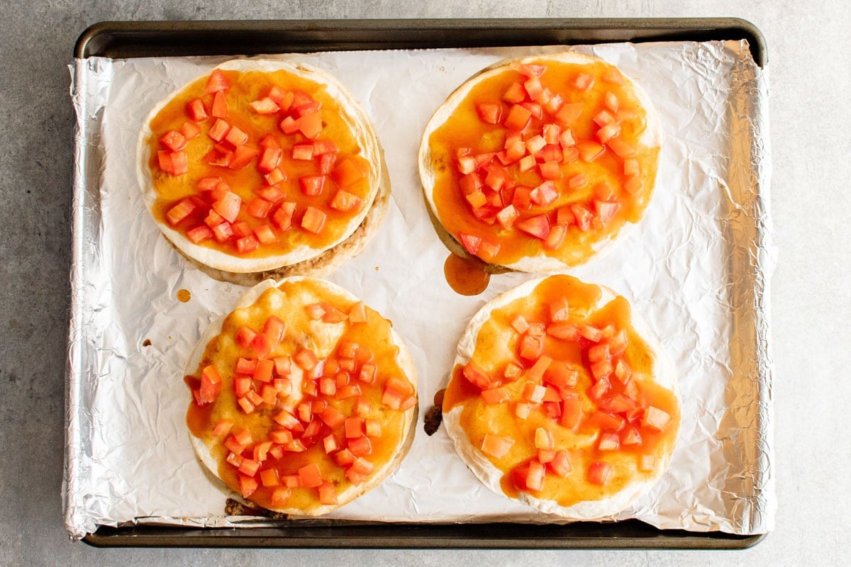 Enchilada sauce and diced tomatoes on a flour tortilla.