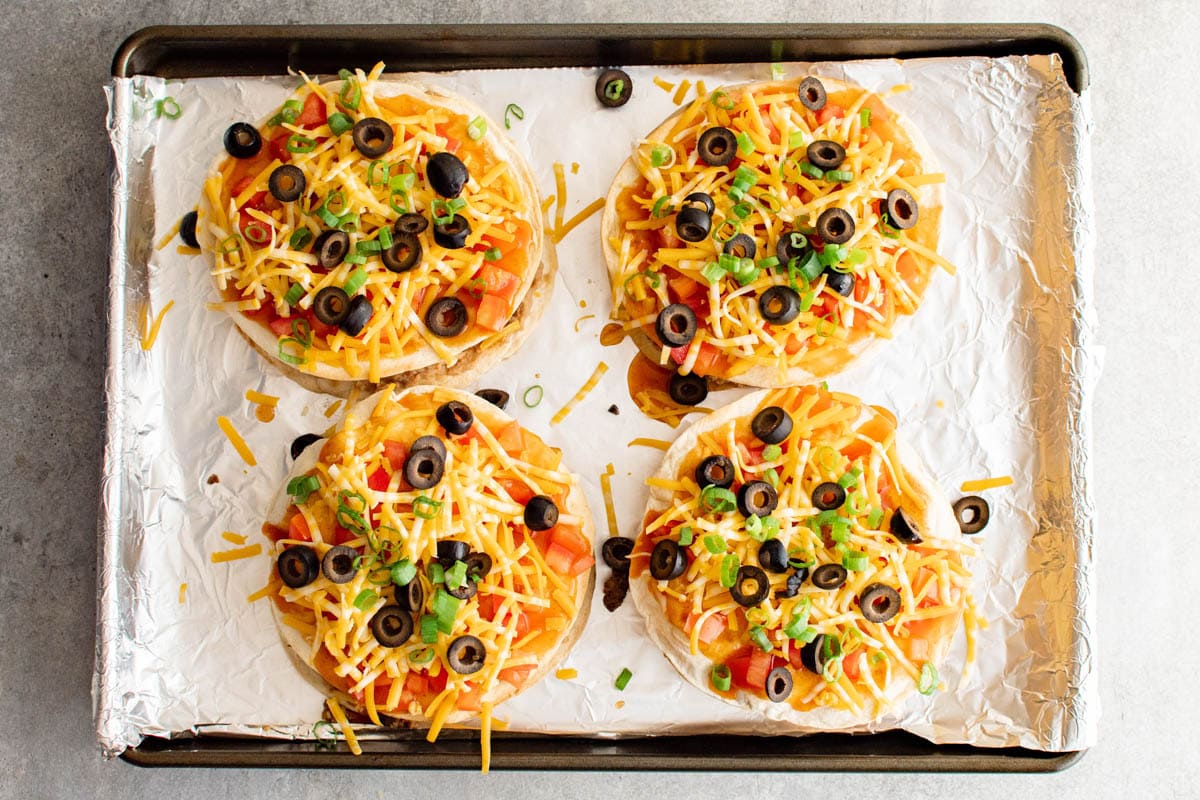 Pre-cooked Mexican pizzas on a foil covered baking sheet.