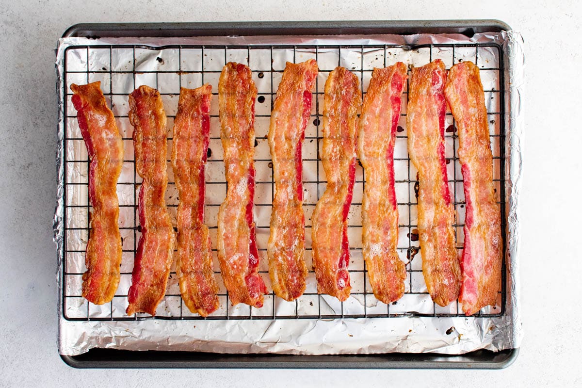 Cooked bacon on a baking sheet with a baking rack.