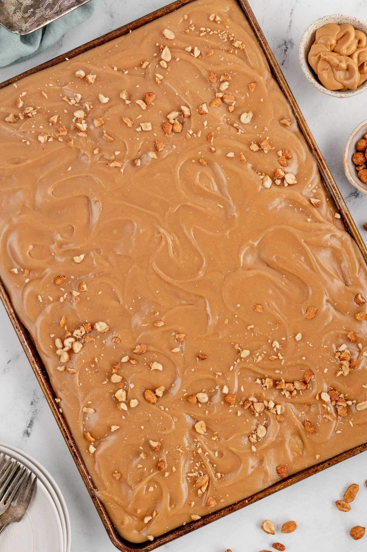 Peanut butter cake with peanut butter and marshmallow frosting on a sheet pan. Topped with crushed peanuts.