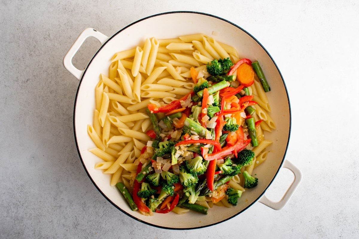 Vegetables and penne pasta in a skillet.