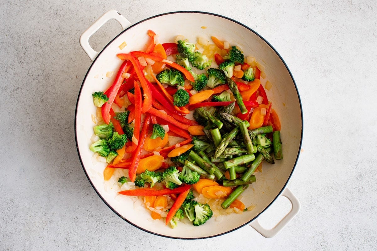 Bell pepper, asparagus, broccoli, carrots and onions in a skillet.
