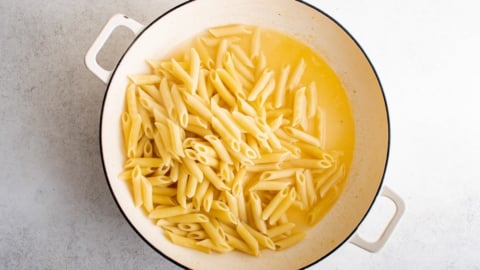 Penne pasta in a lemon butter sauce in a skillet.