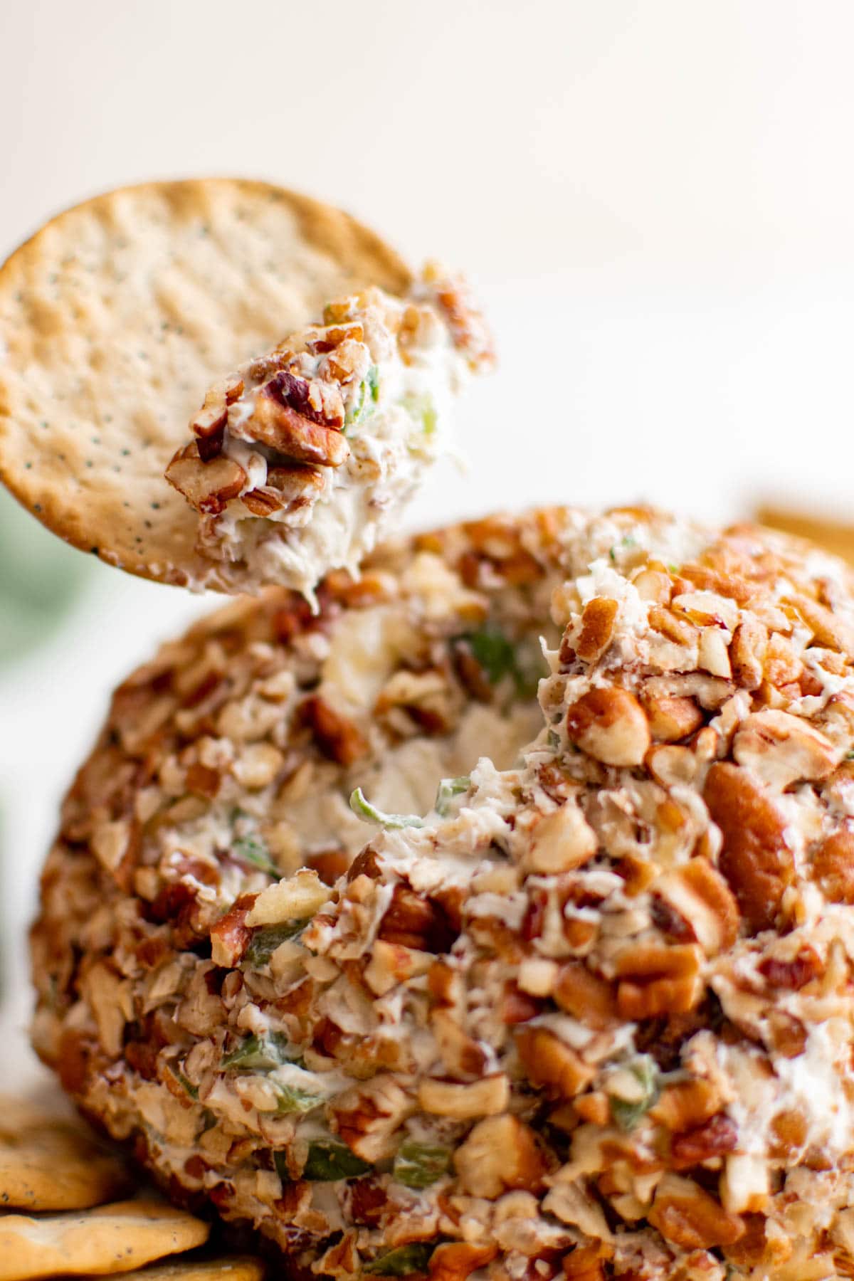 Cheese ball covered in pecans and a crackers with a small bit of dip.