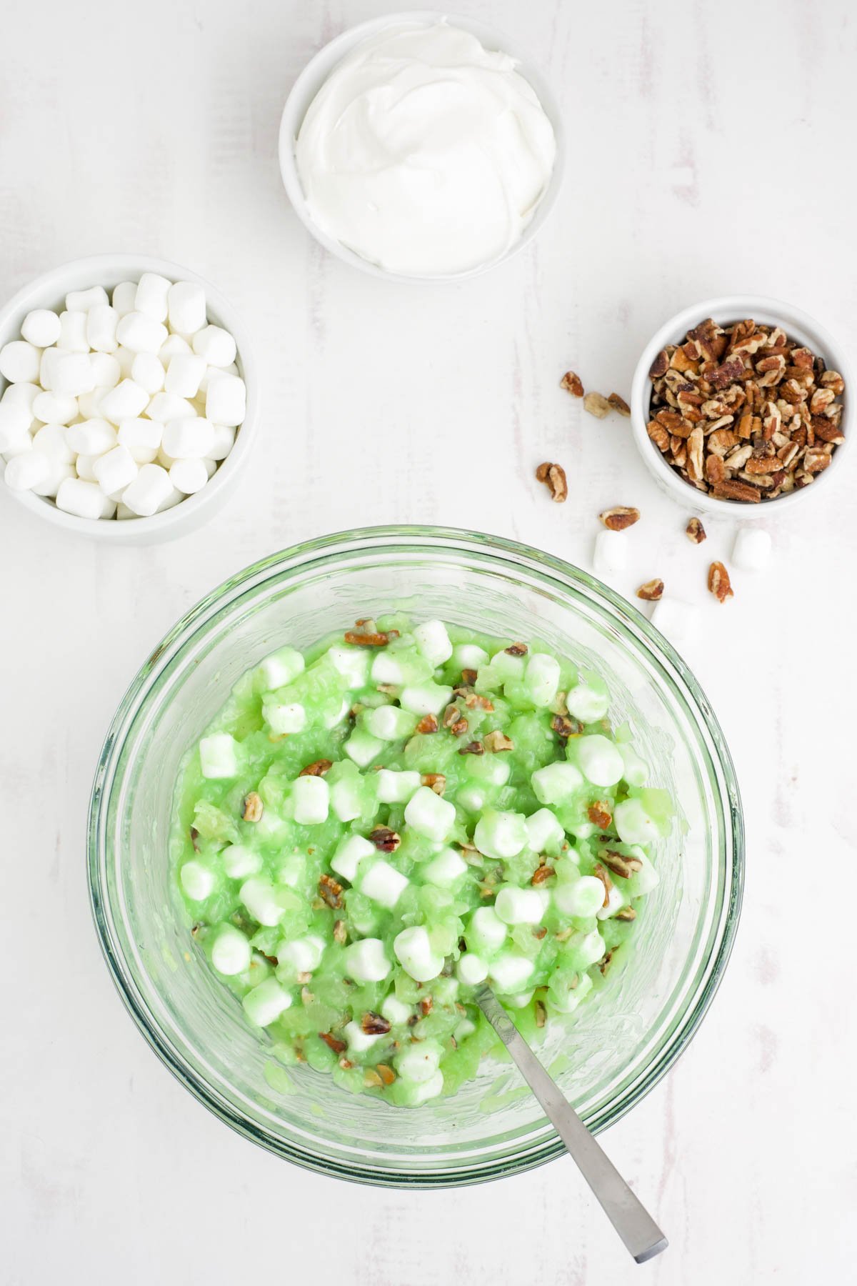 Bowl with pistachio pudding, pineapple, marshmallows and nuts.