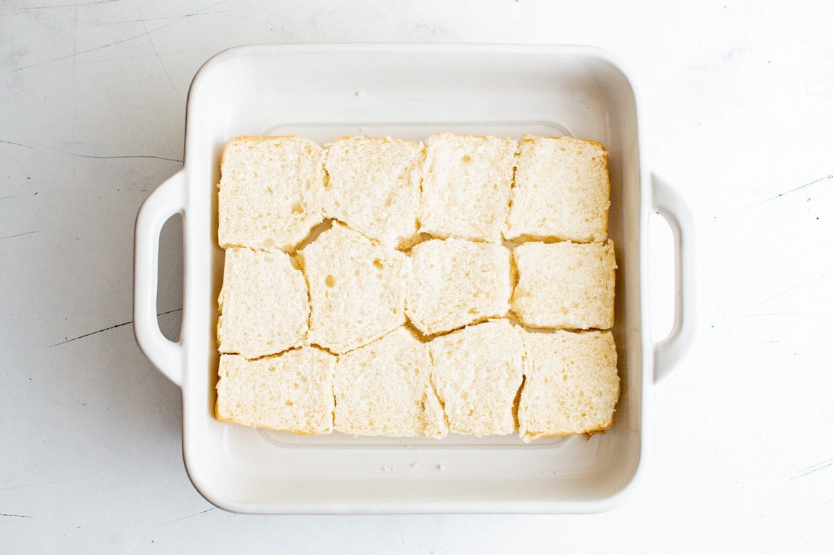 The bottom half of a slab of Hawaiian Rolls in a white baking dish.