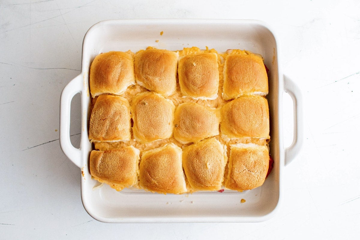 Baked sliders in a white casserole dish.
