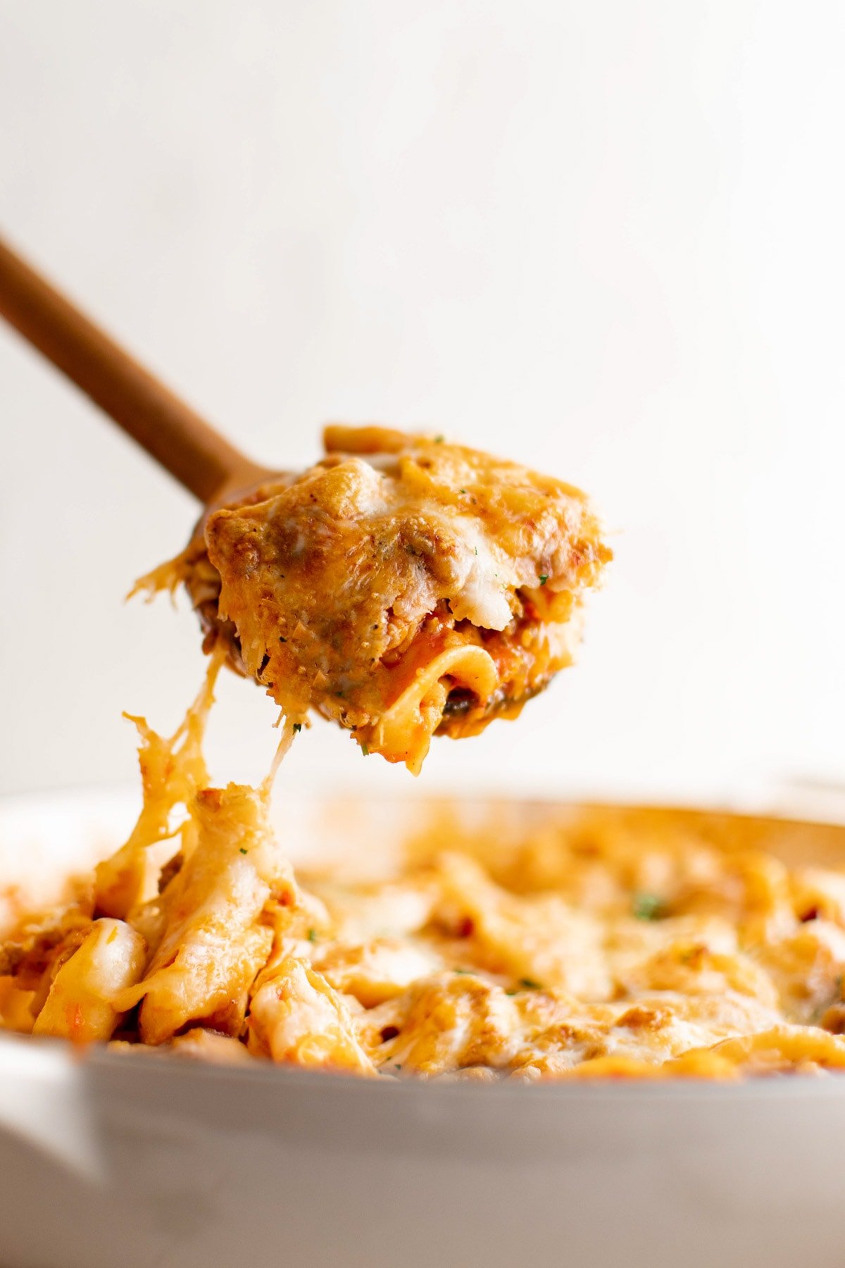 Tortellini on a wooden spoon being served out of a pan.