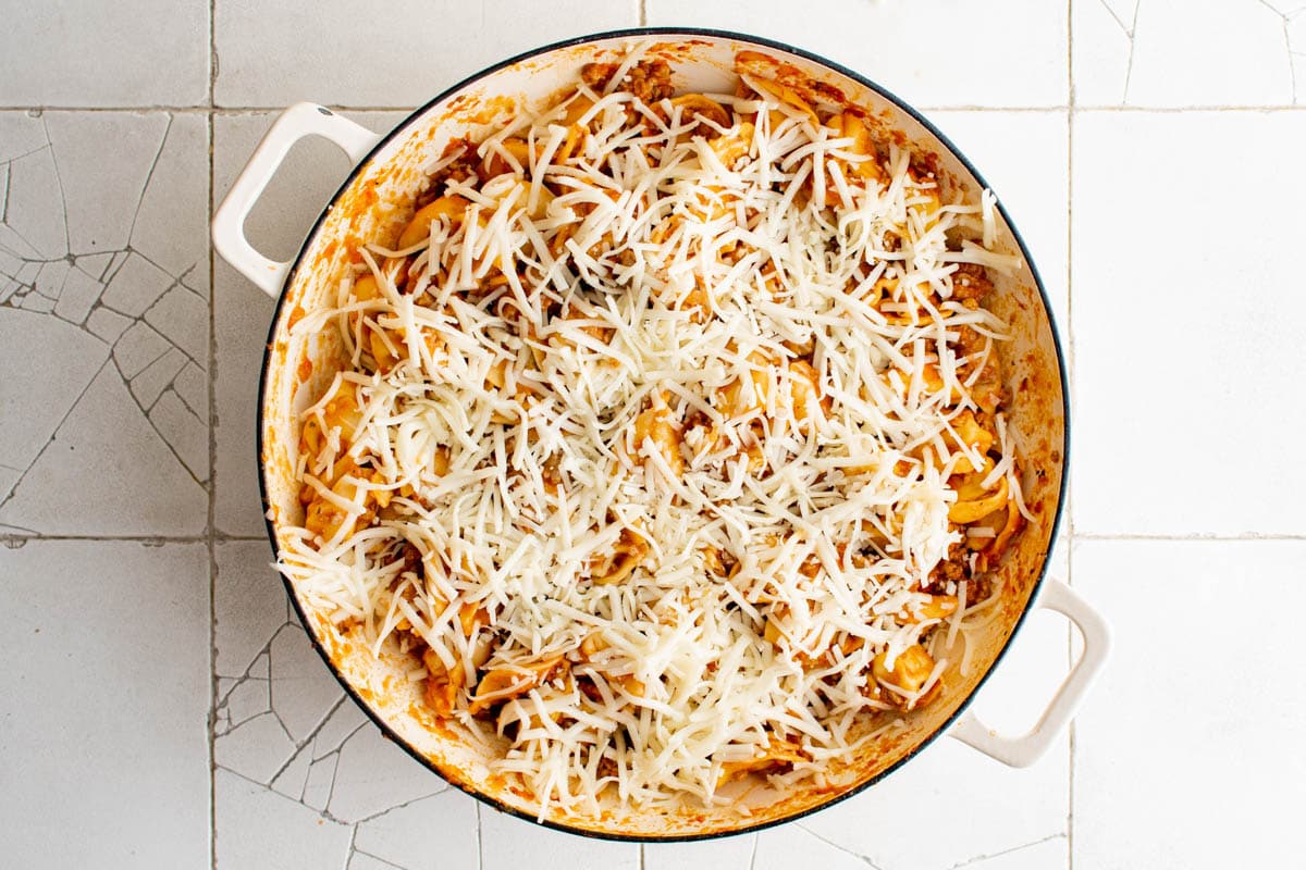 Tortellini and sausage in a skillet with broiled cheese.