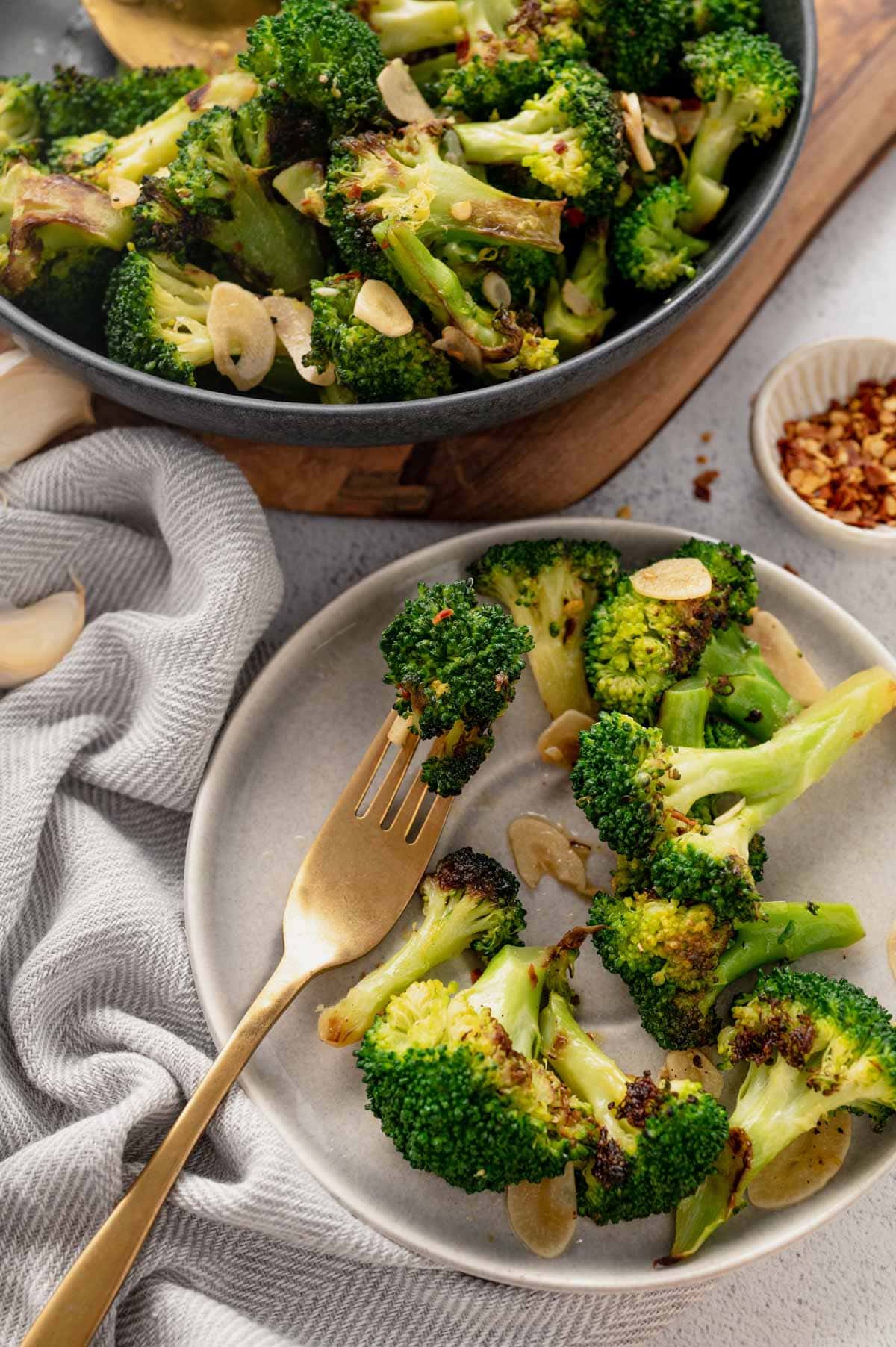 Sauteed broccoli with red pepper flakes and garlic on a plate with a fork.