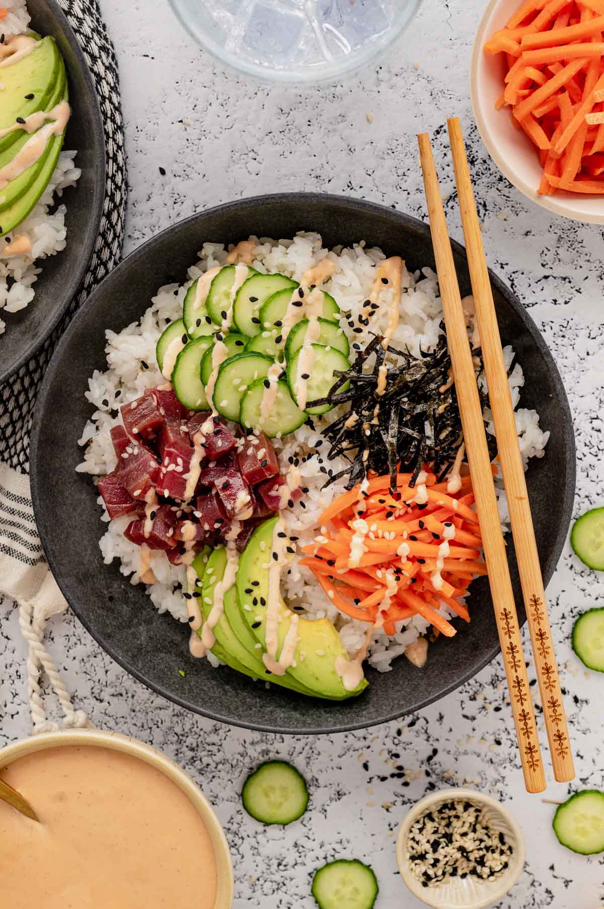 White rice, cucumbers, seaweed, carrots and sashimi tuna in a bowl.