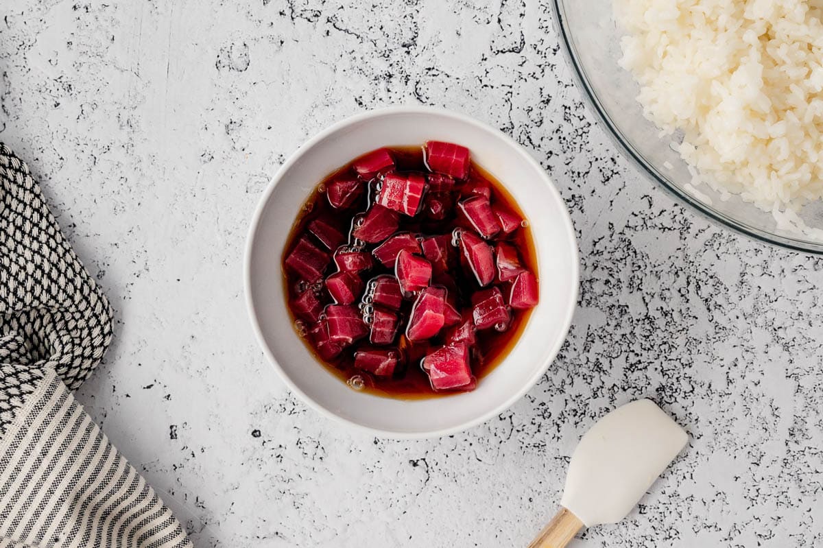 Raw tuna sushi in a bowl of soy sauce.