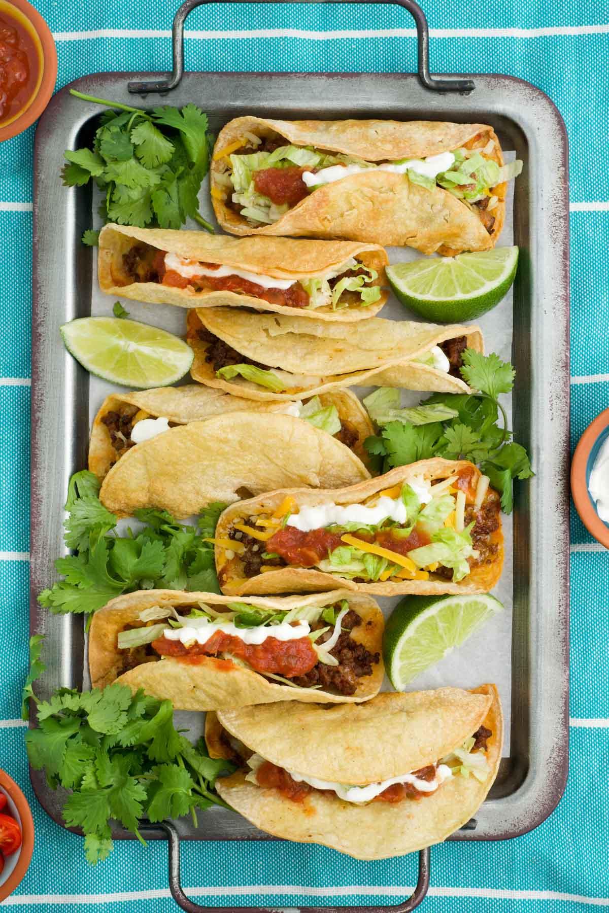 Air fried tacos with corn tortillas, ground beef and cheese on a metal tray.