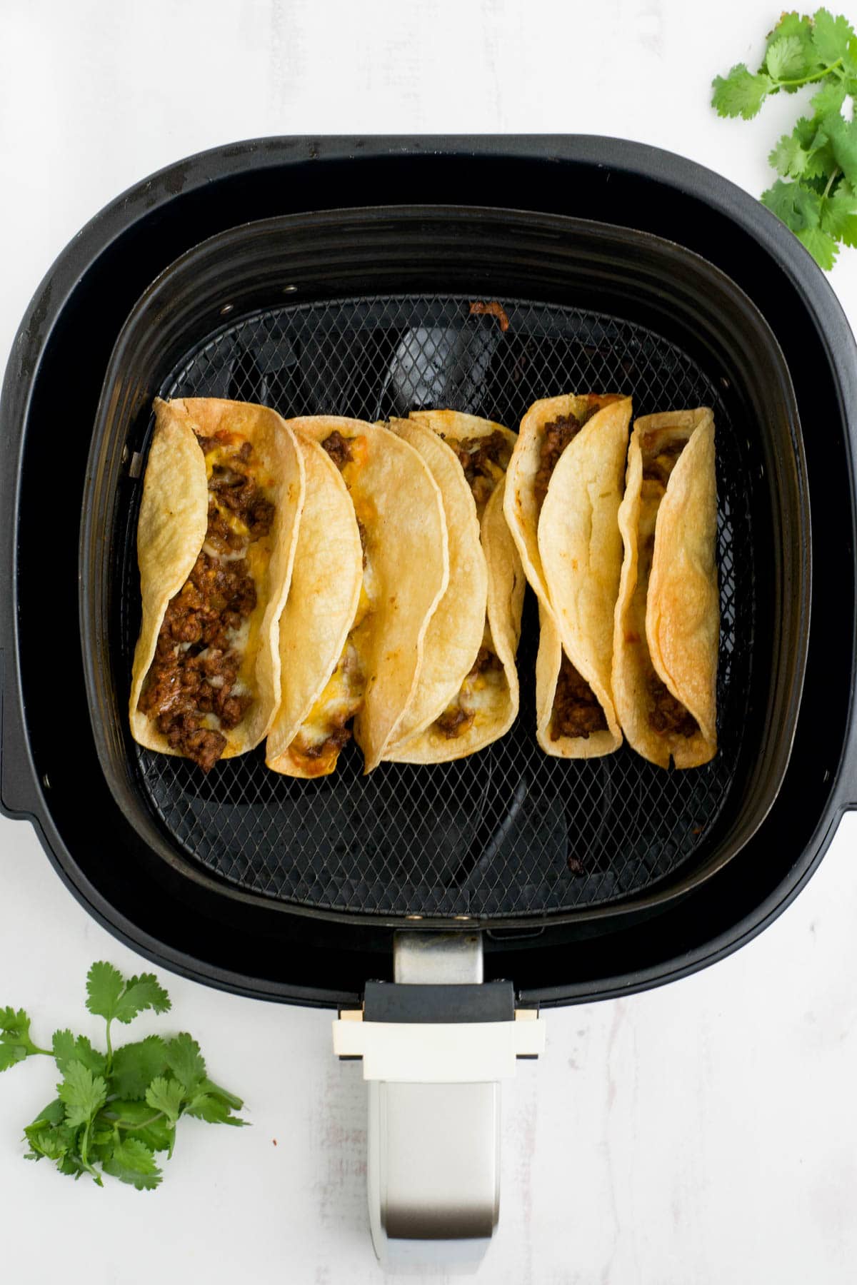 Air fryer tacos in an air fryer basket.