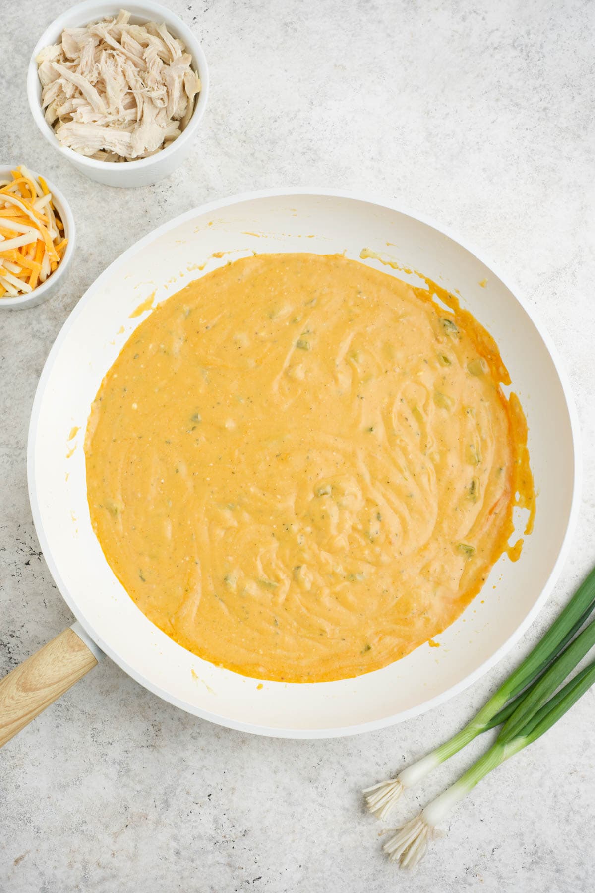 Cheese added and melted into sauce in a white skillet.