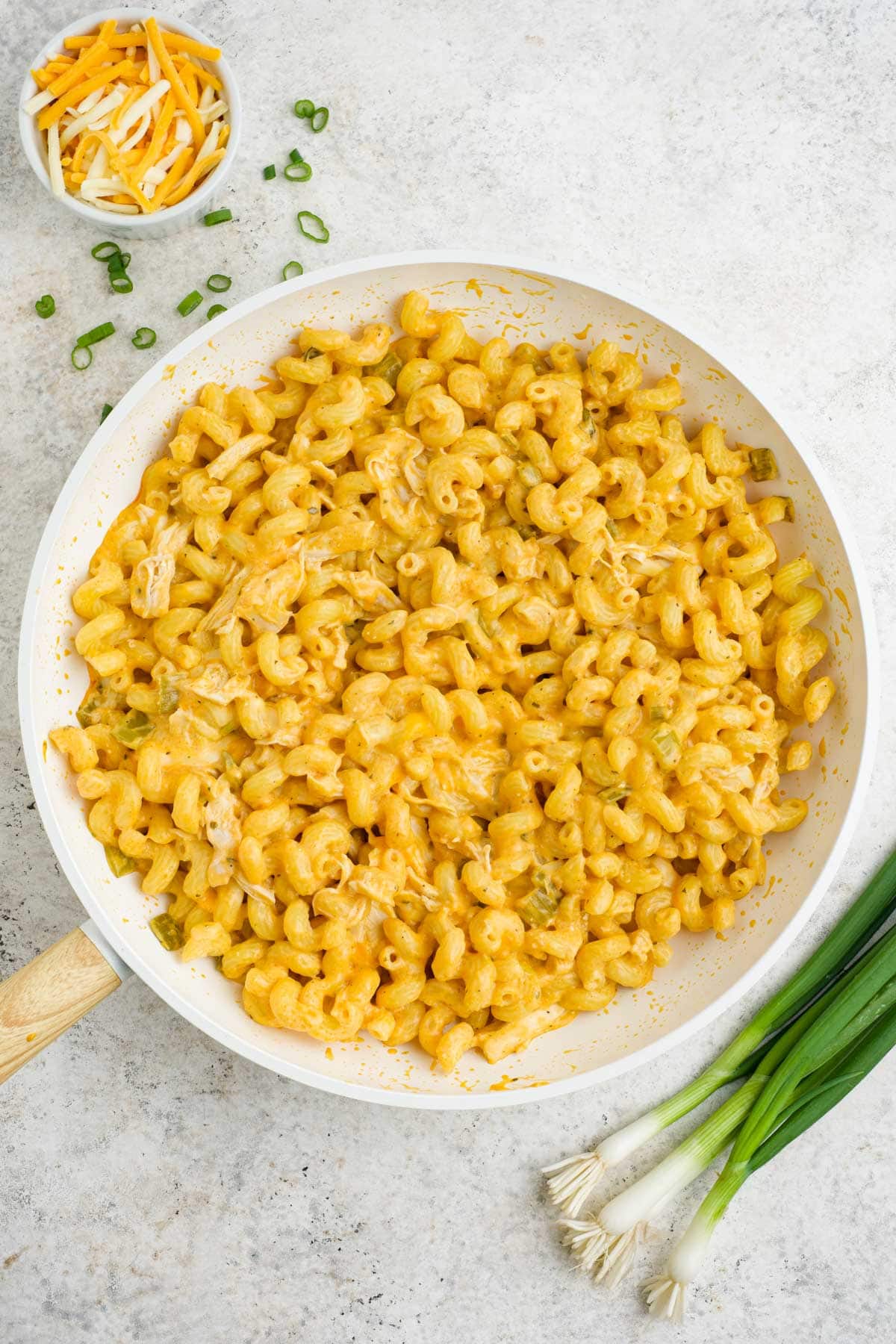 Pasta combined with chicken and cheese sauce in a white skillet.