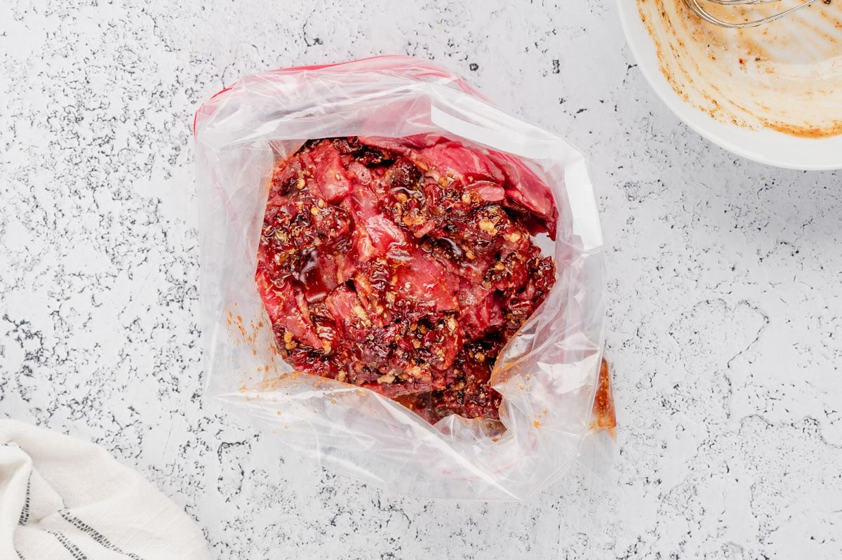 Steak marinating in adobo and spices, in a plastic bag.