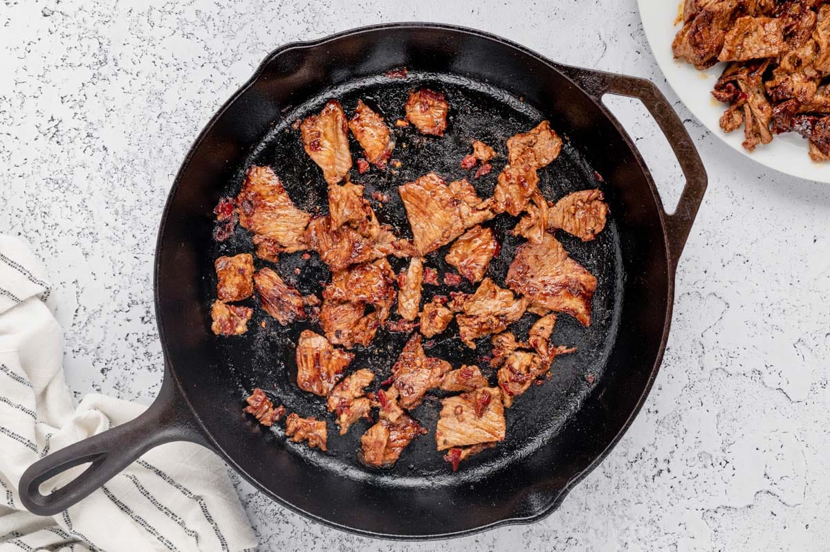 Steak slices cooking in a skillet.