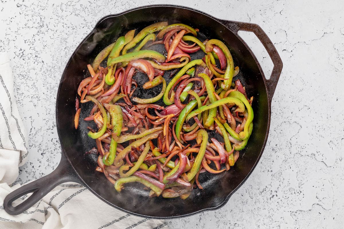 Charred bell pepper and onion strips in a skillet.