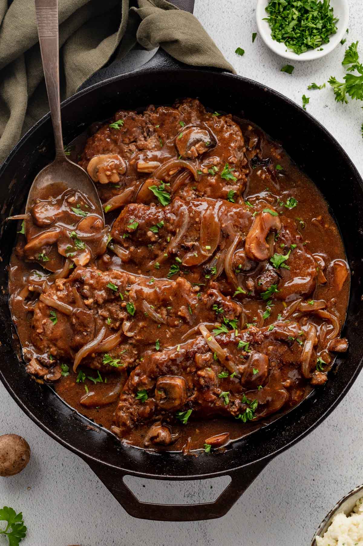 Sauteed cube steaks with gravy, onions and mushrooms in a cast iron skillet.