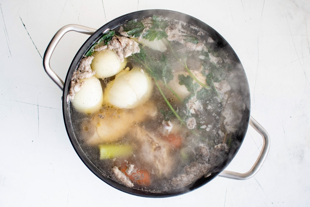 Liquid boiling, onions, parsley, chicken, celery and carrots in a large soup pot.