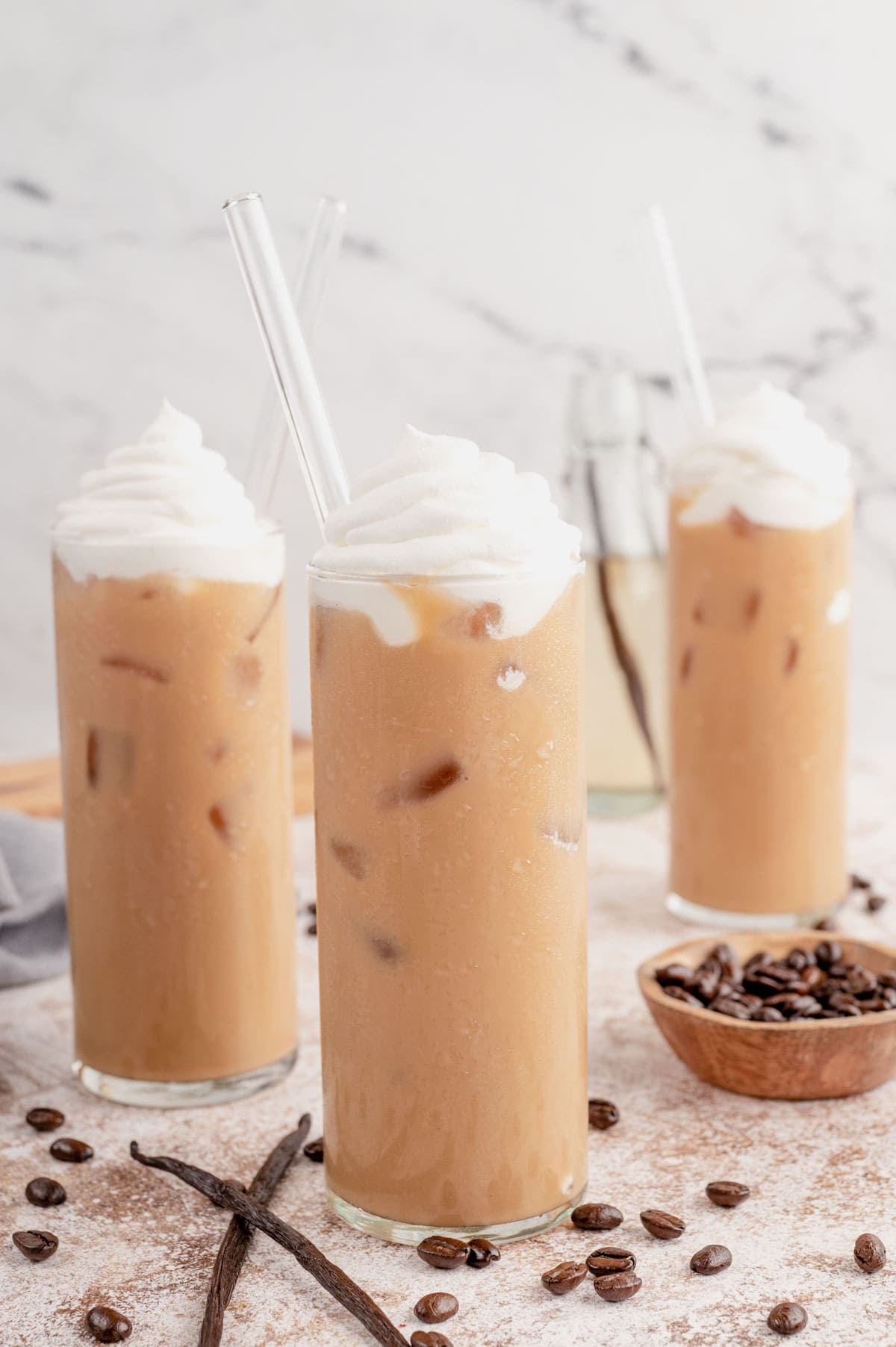 Three glasses of iced coffee with whipped cream and straws.