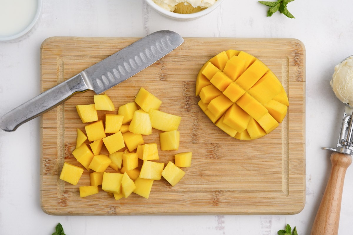 Diced mango on a cutting board with a knife.