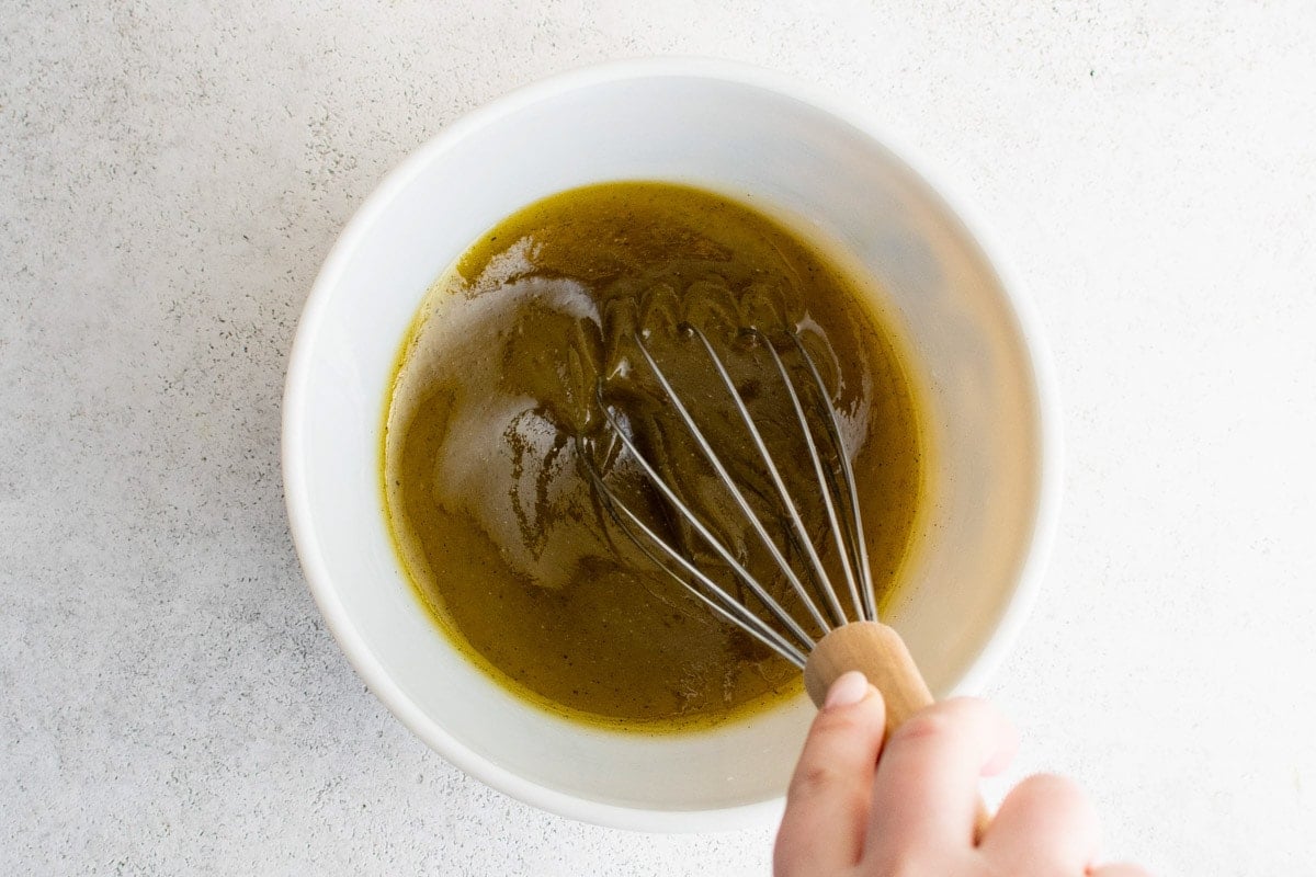 Whisking oil and vinegar together in a small bowl.