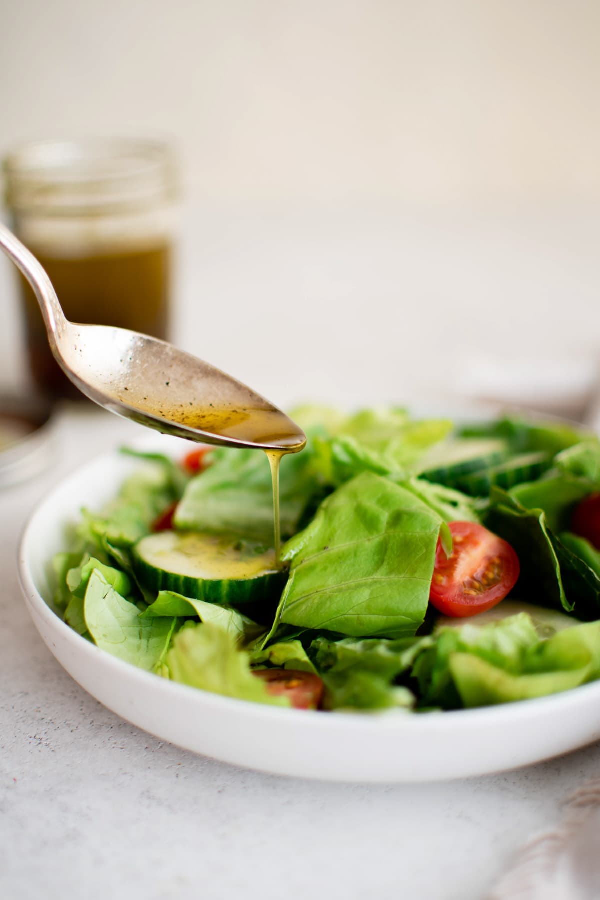 Oil and vinegar dressing drizzled over a salad with a spoon.