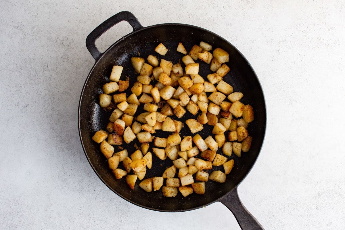 Cast iron skillet with cooked diced potatoes.