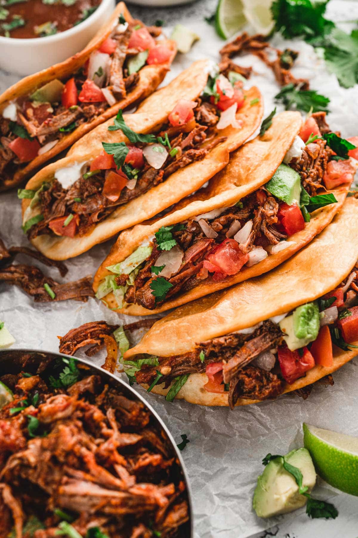 Shredded beef tacos in crispy shels with pico de gallo on top.