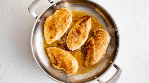 Seared chicken breasts in a silver skillet.