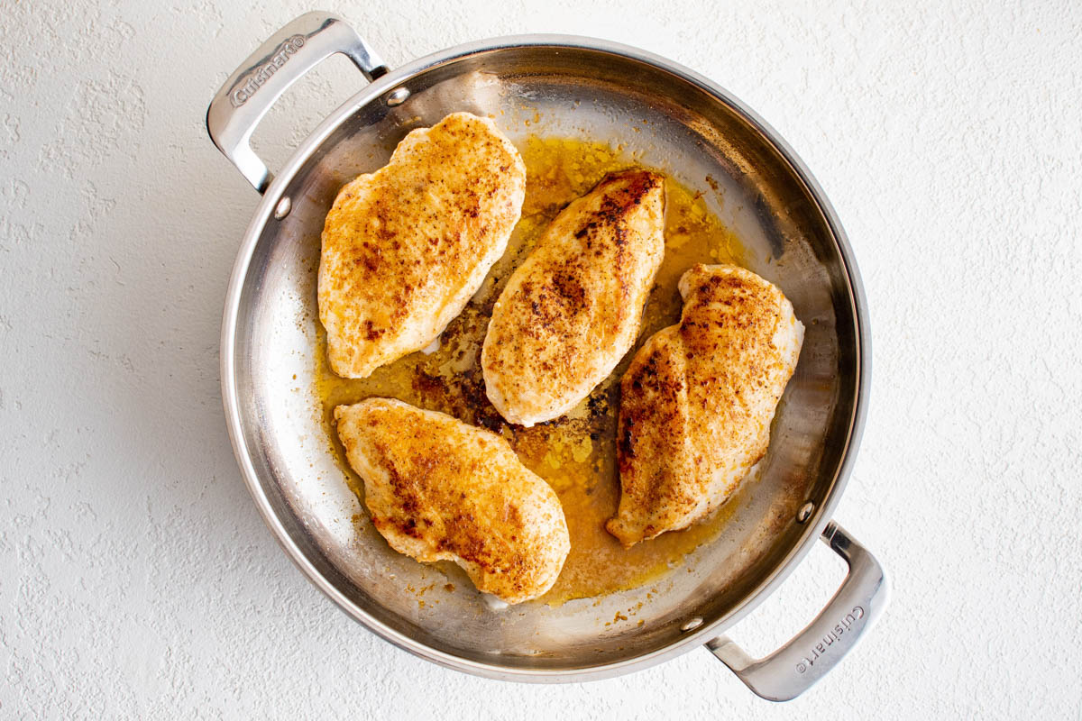 Seared chicken breasts in a silver skillet.