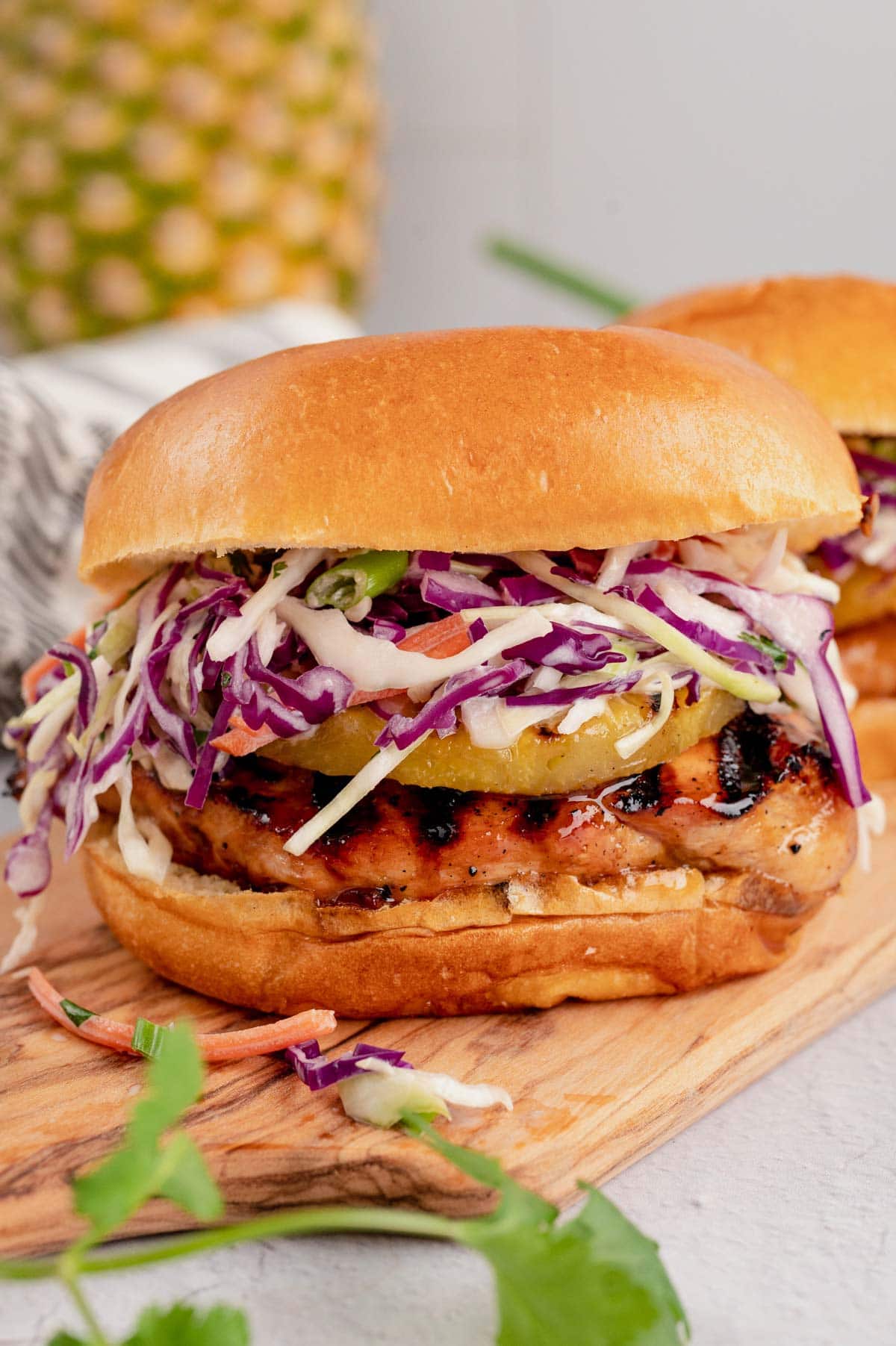 teriyaki chicken sandwich with coleslaw and pineapple.