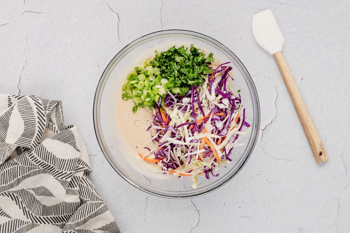 Shredded cabbage, green onions and cilantro in a large bowl.