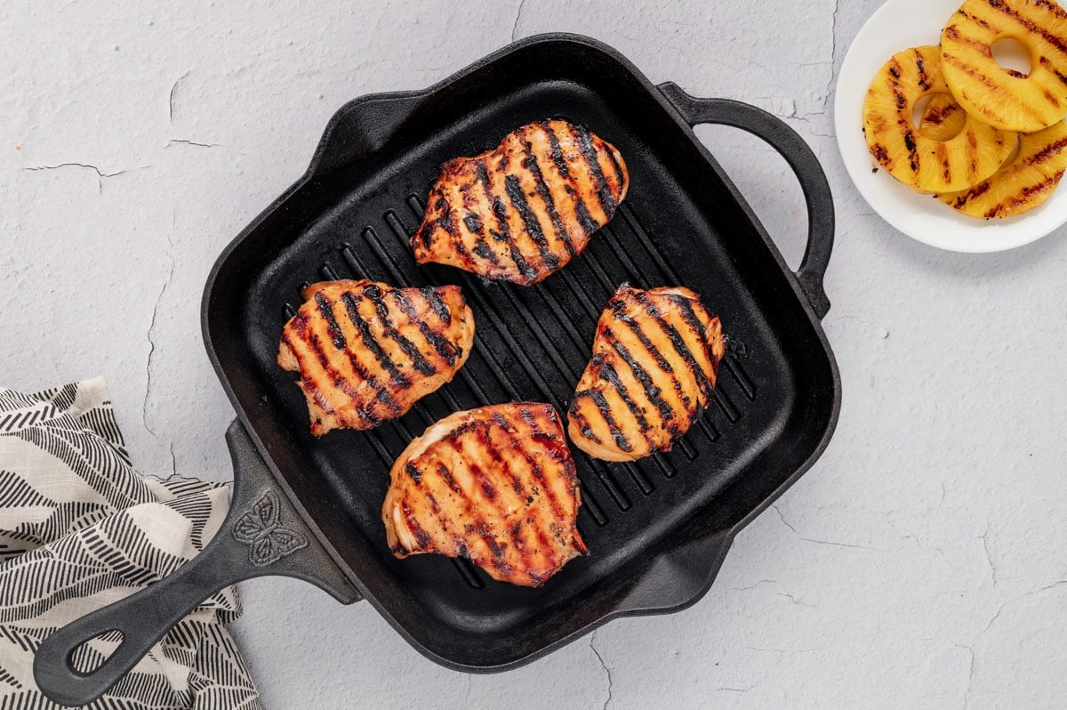 4 Grilled chicken breasts on a grill pan.