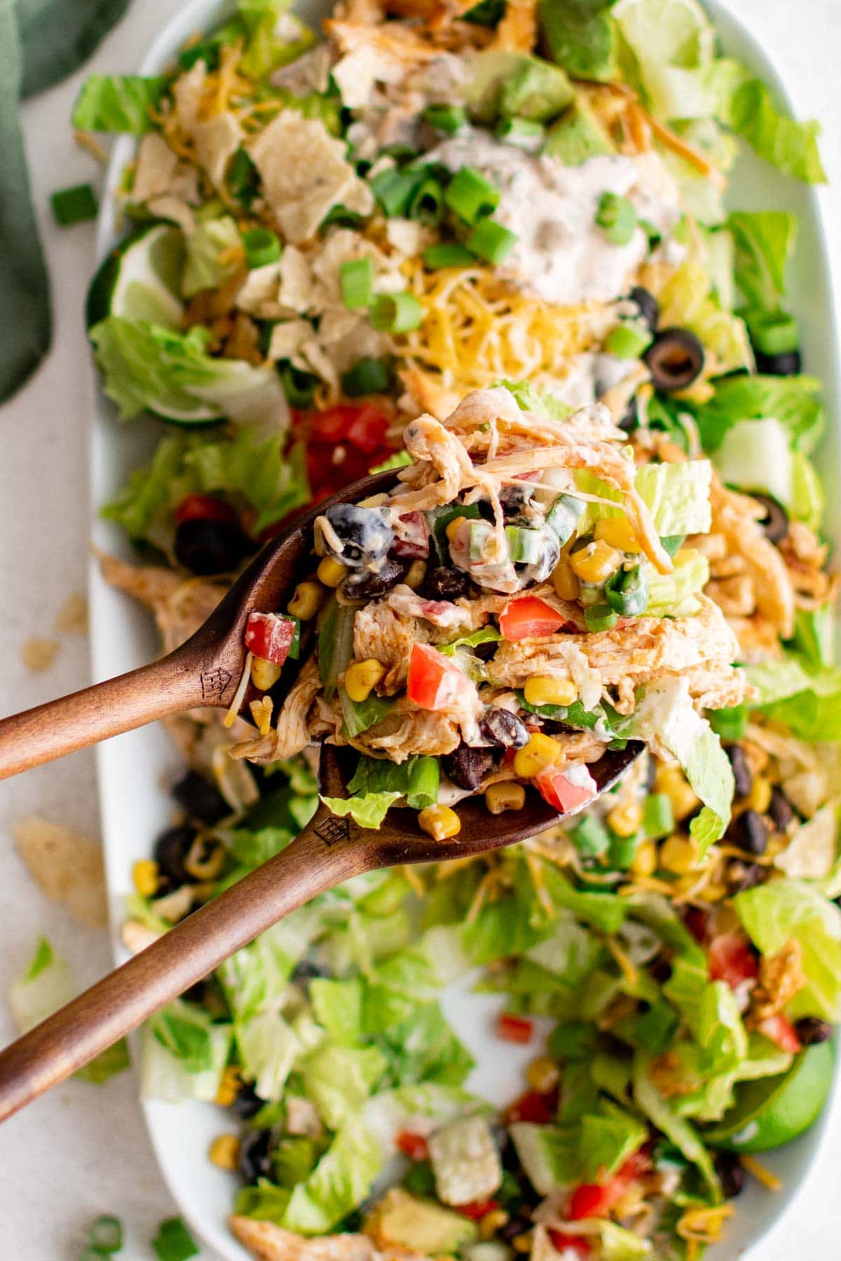 Salad tongs holding up a serving of chicken taco salad.