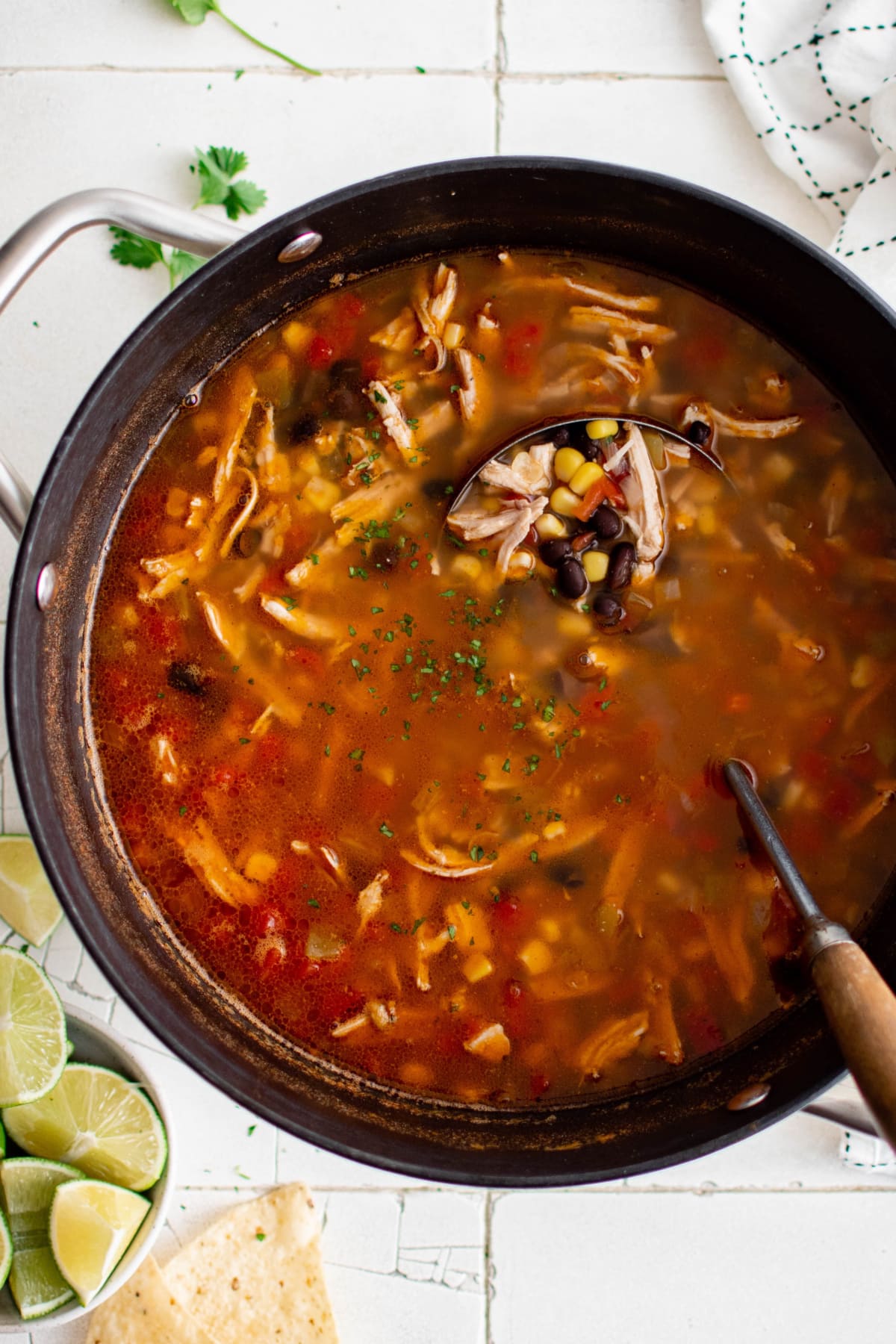 A large pot of soup with chicken, corn and black beans.