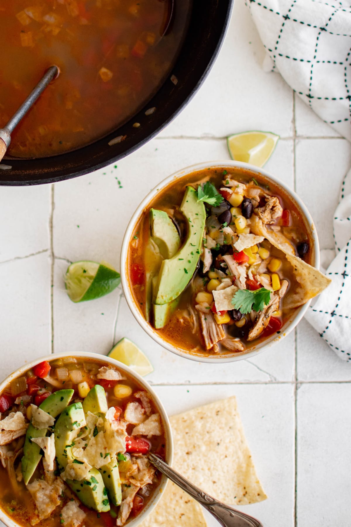 Small bowls of tortilla soup with tortilla chips and sliced avocado.