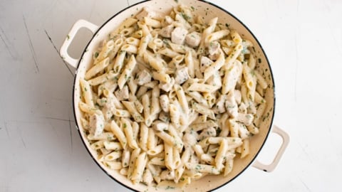 Creamy penne pasta with chicken in a large skillet.