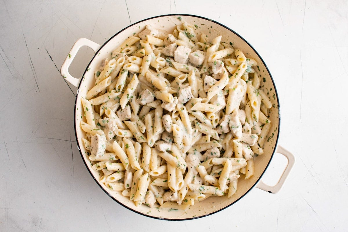 Creamy penne pasta with chicken in a large skillet.