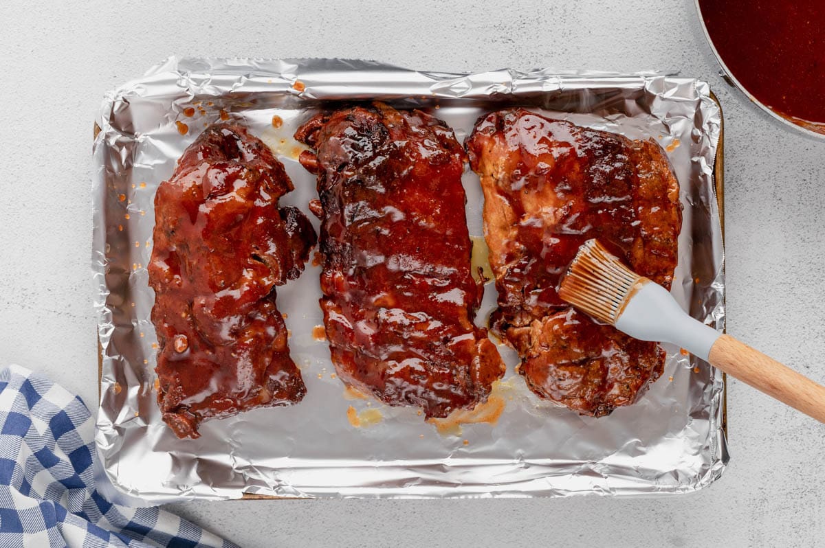 BBQ sauced ribs on a baking sheet. 