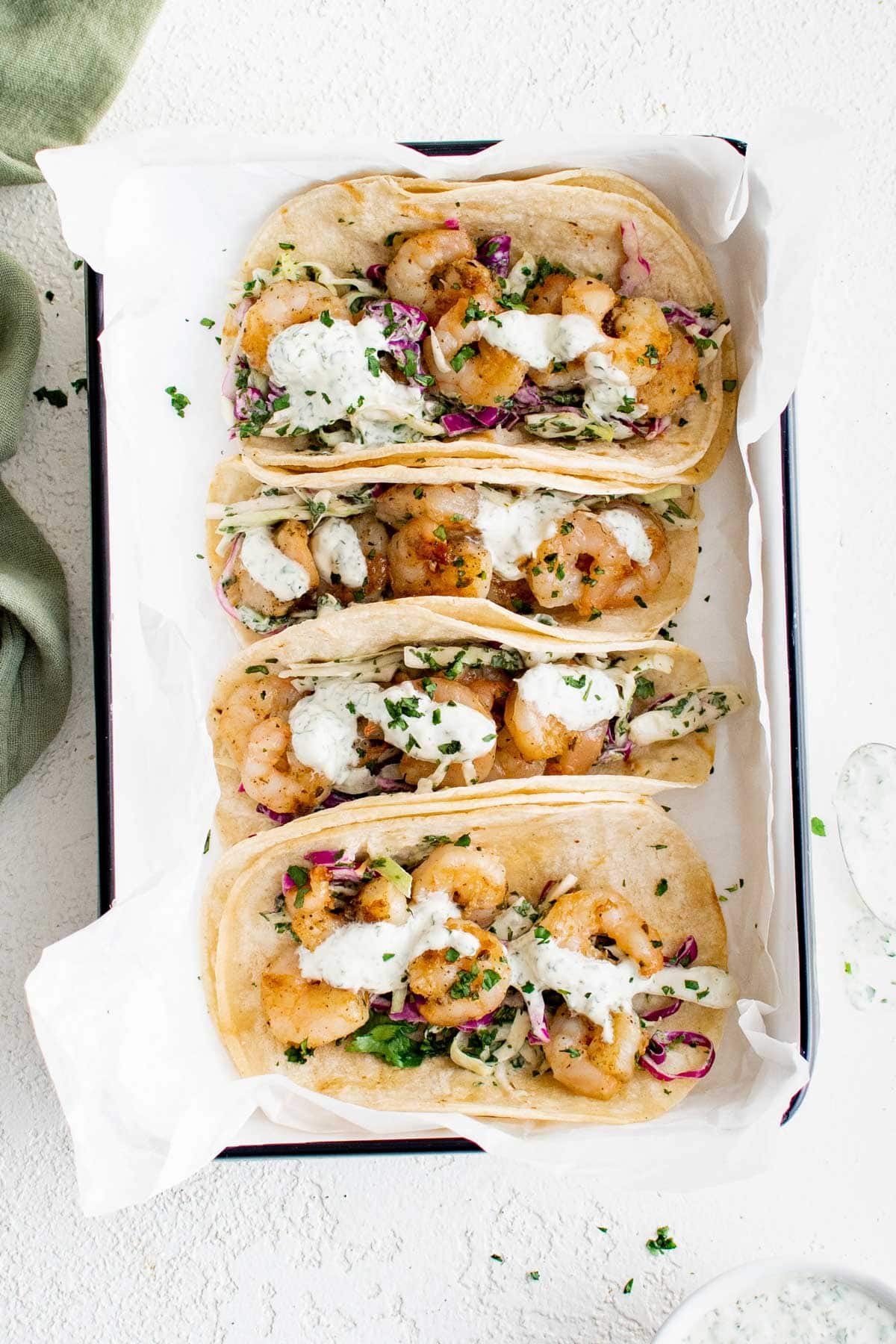 Shrimp tacos with slaw and lime crema in a platter.
