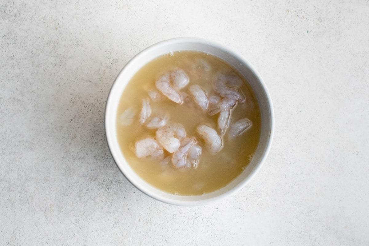 shrimp in lemon juice in a white bowl.