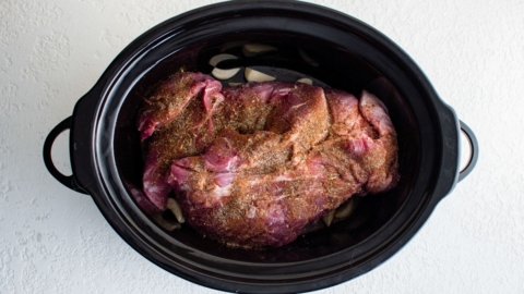 Pork butt roast in a slow cooker with spices.