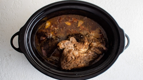 Corked pork roast in a slow cooker with juices.