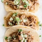 Carnitas in corn tortilla shells with onions and cilantro.