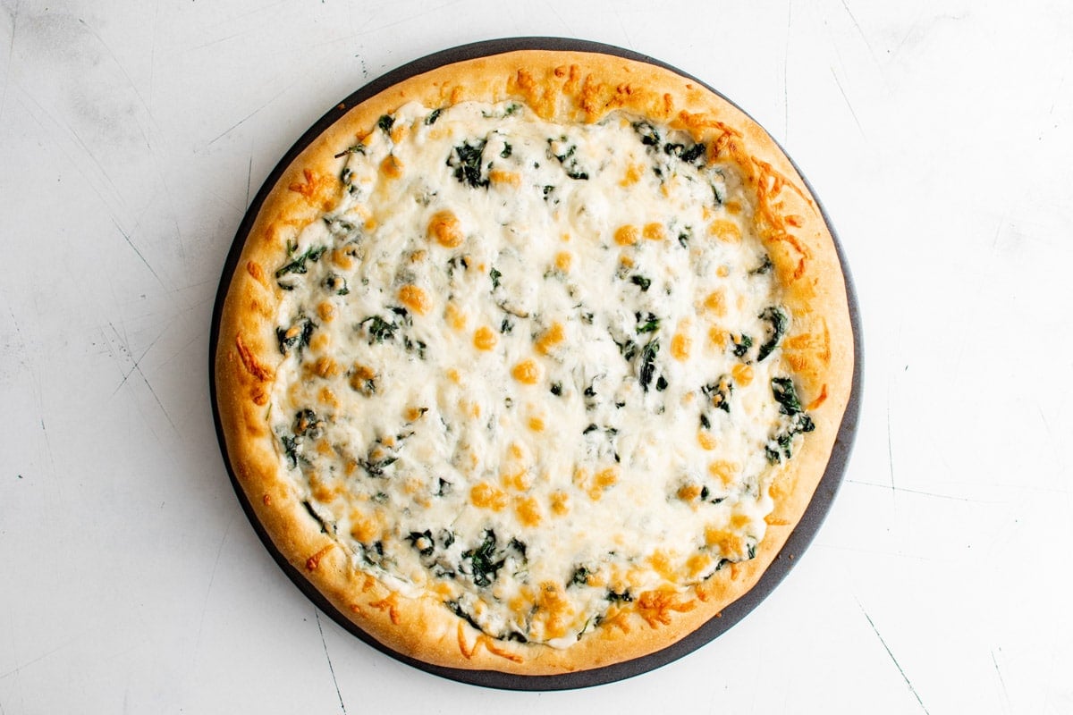 Cooked spinach alfredo pizza.
